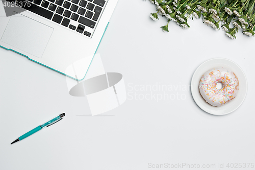 Image of Office desk table with computer, supplies, flowers