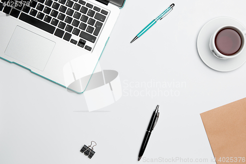 Image of Office desk table with computer, supplies, flowers and coffee cup.