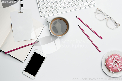 Image of Office desk table with computer, supplies, phone and coffee cup.