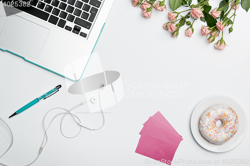 Image of Office desk table with computer, supplies, flowers