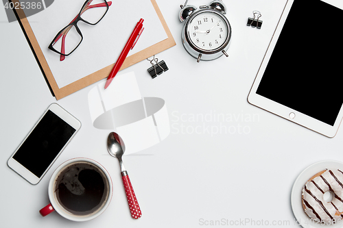 Image of Office desk table with laptop, supplies, phone and coffee cup.