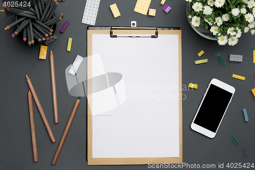 Image of Office desk table with pencils, supplies, phone and flowers