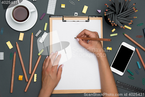 Image of Office desk table with pencils, supplies, phone and female hands