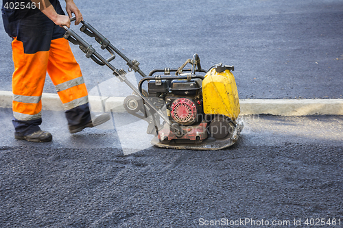 Image of Worker use vibratory plate compactor 