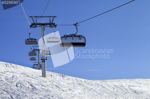 Image of Ski-lift and off-piste slope in sun cold day