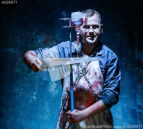 Image of Bloody Halloween theme: crazy killer as butcher with saw