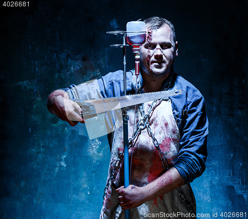 Image of Bloody Halloween theme: crazy killer as butcher with saw