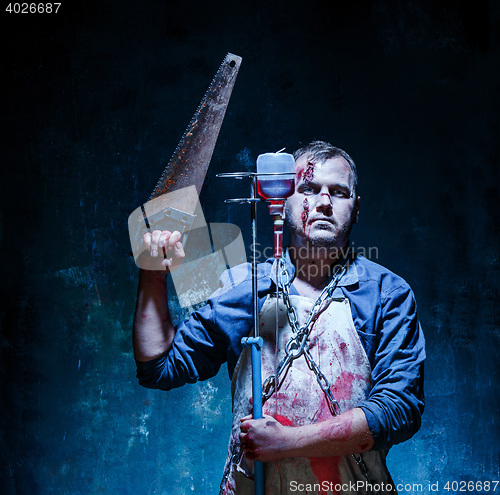 Image of Bloody Halloween theme: crazy killer as butcher with saw