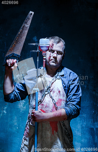 Image of Bloody Halloween theme: crazy killer as butcher with saw