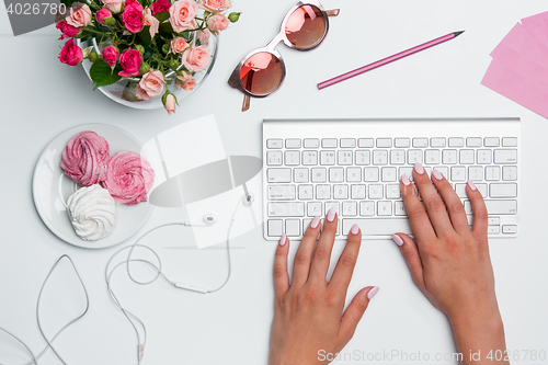 Image of Office desk table with female hands, computer, supplies, flowers