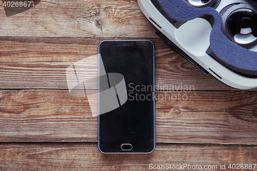 Image of Modern smartphone with empty screen and virtual reality goggles