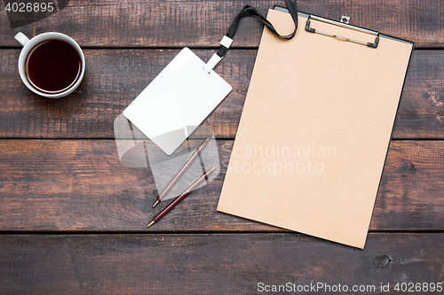 Image of Office wooden table with pens, tablet for notes and cup