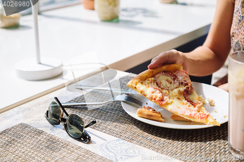 Image of Unrecognizable woman eating pizza in cafe