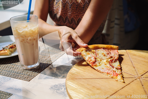 Image of Unrecognizable woman eating pizza in cafe