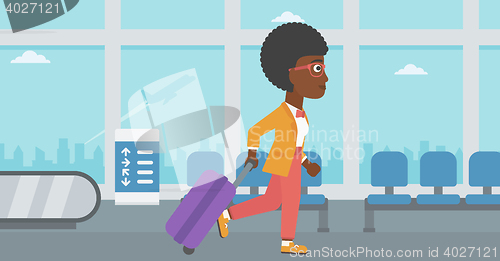 Image of Woman walking with suitcase at the airport.