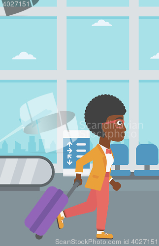 Image of Woman walking with suitcase at the airport.