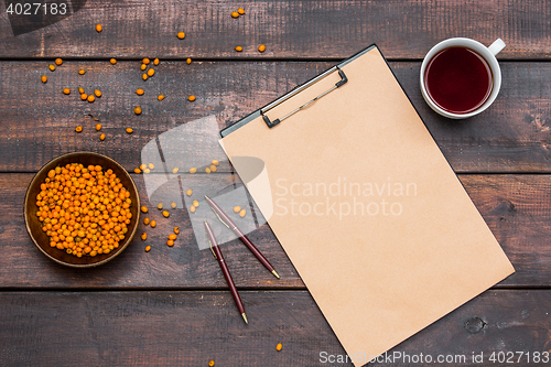 Image of Office desk table with cup, notebook, fresh sea buckthorn berries on wooden table