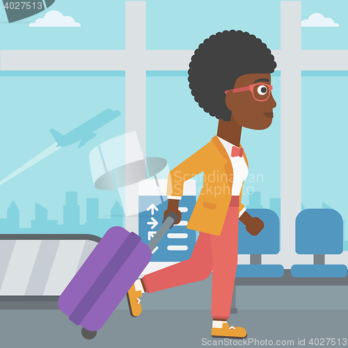 Image of Woman walking with suitcase at the airport.