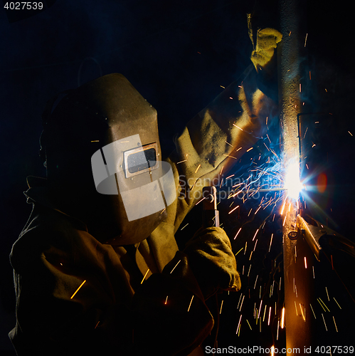 Image of welder worker welding metal by electrode