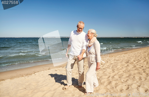 Image of happy senior couple walking along summer beach