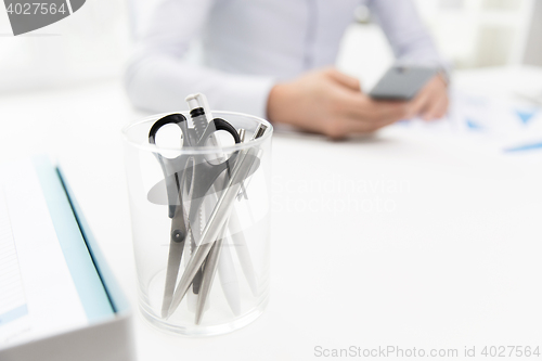 Image of close up of cup with scissors and pens at office