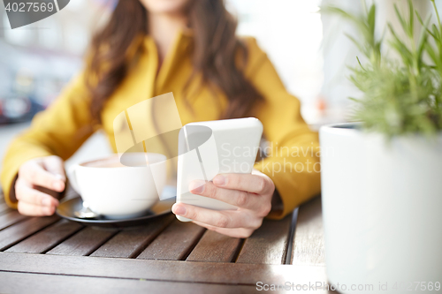 Image of close up of woman texting on smartphone at cafe