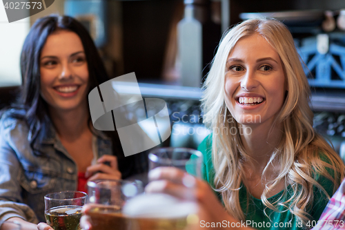 Image of happy female friends drinking beer at bar or pub