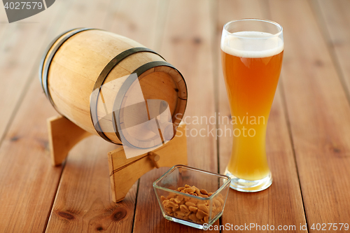 Image of close up of beer glass, peanuts and wooden barrel