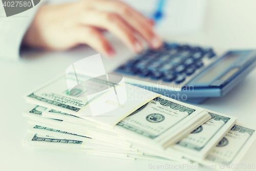 Image of close up of hand counting money with calculator