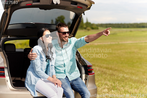 Image of happy couple hugging at open hatchback car trunk
