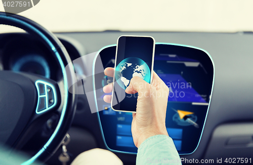 Image of close up of man hand with smartphone driving car