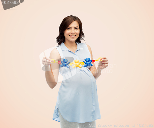 Image of happy pregnant woman holding rattle toy