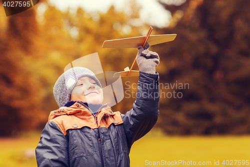 Image of happy little boy playing with toy plane outdoors