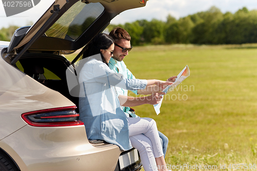 Image of happy man and woman with road map at hatchback car