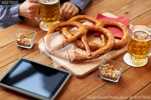 Image of close up of man drinking beer with pretzels at pub