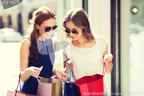 Image of happy women with shopping bags in city