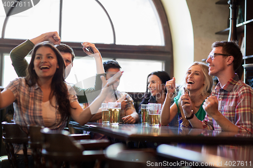 Image of friends with beer watching football at bar or pub