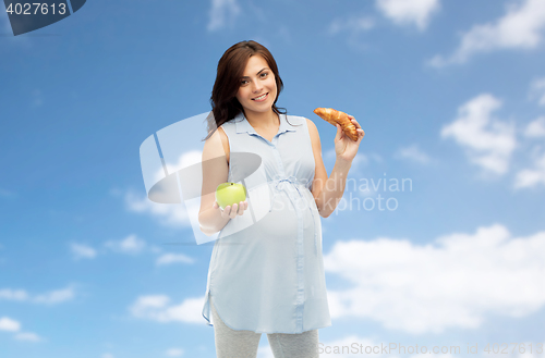 Image of happy pregnant woman with apple and croissant