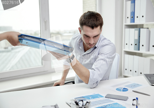 Image of businessman taking papers from secretary in office