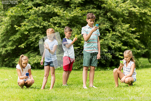 Image of kids with smartphones playing game in summer park