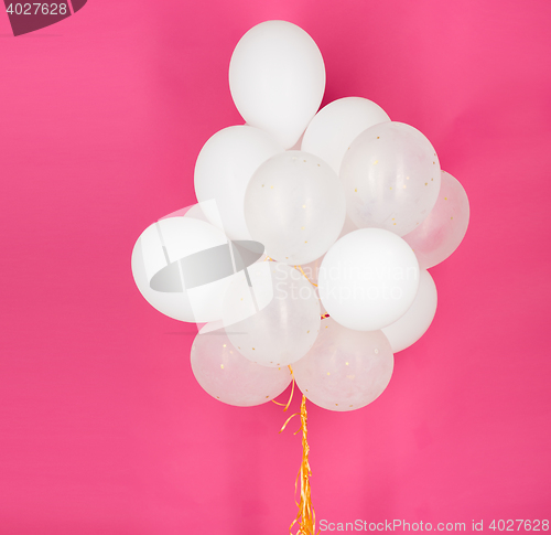 Image of close up of white helium balloons over pink