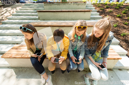 Image of happy teenage friends with smartphones outdoors