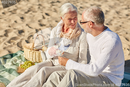 Image of happy senior couple having picnic on summer beach