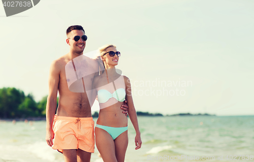 Image of happy couple in swimwear walking on summer beach