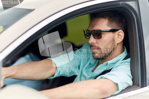 Image of young man in sunglasses driving car