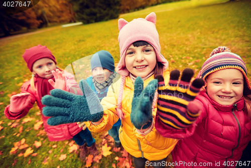 Image of happy children waving hands in autumn park