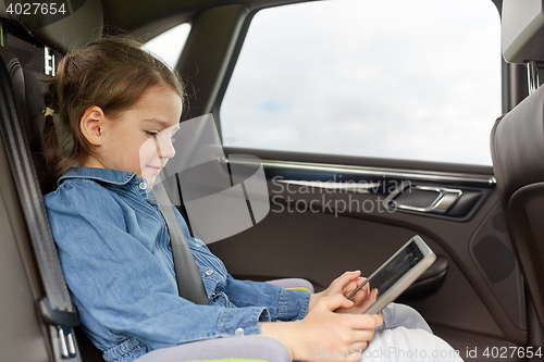 Image of happy little girl with tablet pc driving in car