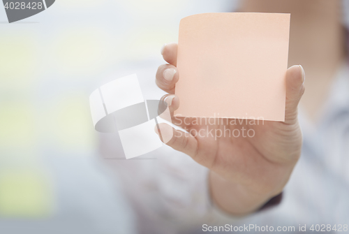 Image of Hand of woman holding sticky note with empty space