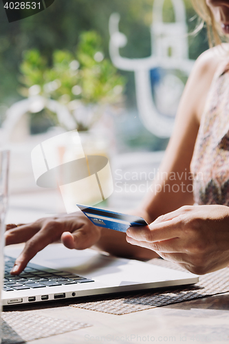 Image of woman using laptop with credit card in hand