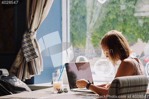 Image of Young short-haired woman using laptop in cafe